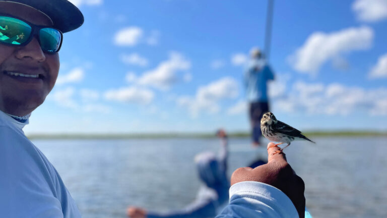 A guide from kay Fly Fishing Lodge has a bird perched on his hand.
